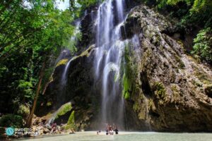 Tumalog Falls in Oslob Cebu featuring a wide curtain-like waterfall cascading over limestone cliffs surrounded by lush tropical greenery