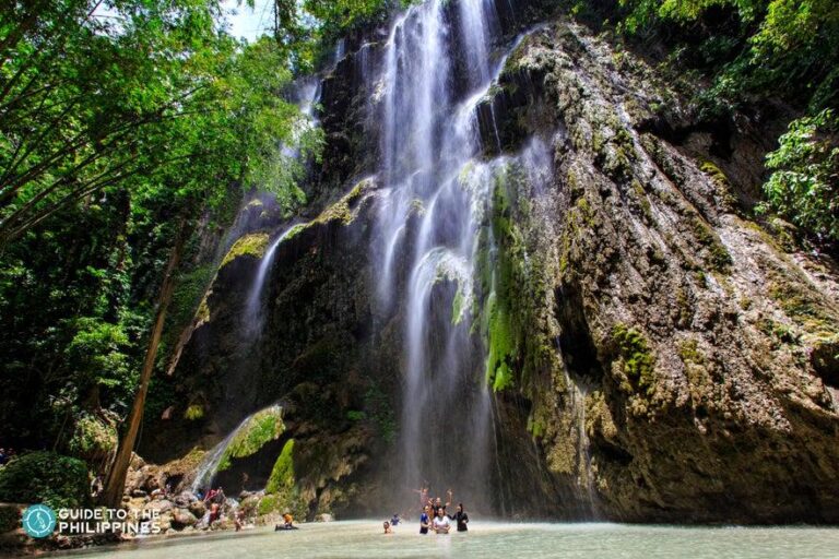 Tumalog Falls in Oslob Cebu featuring a wide curtain-like waterfall cascading over limestone cliffs surrounded by lush tropical greenery